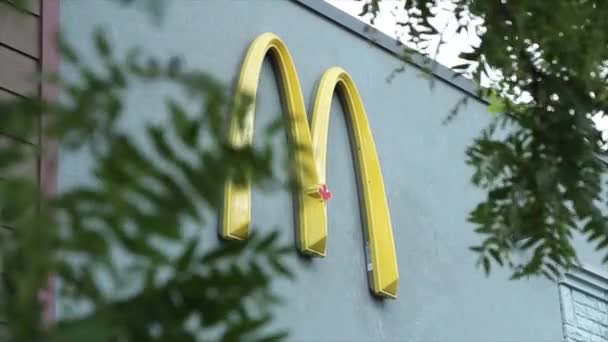 餐厅外墙上的麦当劳拱形黄色M标志 枝叶飘扬 前景广阔 — 图库视频影像