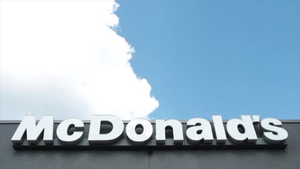 Mcdonaldsライティングキャプションテキストサインロゴ 灰色のレストランの建物の壁に白く 雲が外のフレームの外側の外側を見下ろす後ろに移動します — ストック動画