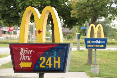 McDonalds yazları biri diğerinin önünde olmak üzere girişteki direklere yazı yazıp kapatıyor.