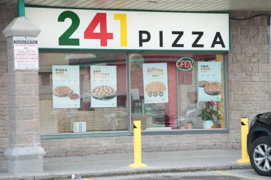 241 pizza dükkanı dükkânı önü pizzacı girişi dikdörtgen amblemi ve yol kaldırımı önünde ve neon açık tabelası var.