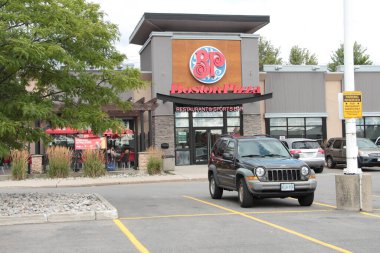 Boston pizza restoranı ve spor barı girişi ve restoranın önünde kırmızı mavi beyaz logo işareti olan teras.