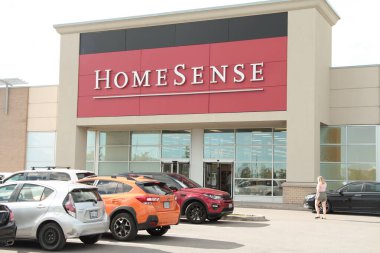 Alışveriş merkezinin ön girişi önünde park yeri olan mağazaya doğru yürüyen bir müşteri var.