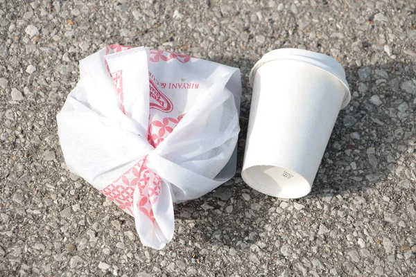 空的白色咖啡杯 盖在捆绑的塑料袋上 圆形早餐垃圾 铺在阳光灿烂的水泥混凝土路面上 — 图库照片
