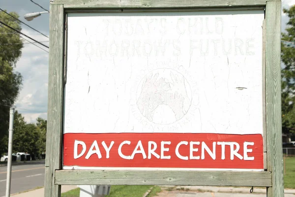 day care centre center sign on wood posts with wood frame outside exterior outdoors with road behind, todays child tomorrows future
