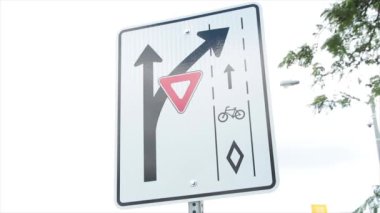 Bisiklet yolu kavşağı kapalı bükülün dikdörtgen trafik levhası beyaz siyah kırmızı gökyüzü ve ağaç dalları arkasında