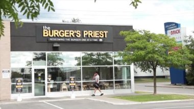 Hamburgercinin restoranının ortak girişi. Müşteri girişi. Logo işaretli, önünde park yeri olan siyah pencereler.