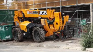 jcb sertifikalı ekipman sarı makine makine inşaat lastikleri dış tarafta çitlerin arkasında çalışan işçiler
