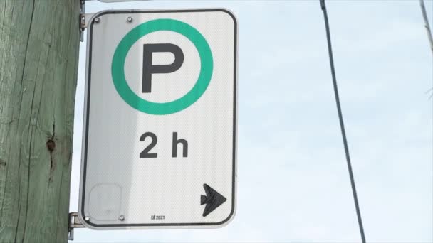 停车时间为2小时 白色黑色竖直矩形标志 箭头和P在木柱上的绿色圆圈上 蓝天在后面 — 图库视频影像