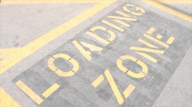 Yazın çimento üzerine siyah üzerine sarı yazılar yazarak dışarıda beton döşeme çimento üzerine yazılıydı. Üzerinden araba gölgeleri geçiyordu.