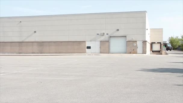 白いドアおよび大きい1つの物語のベージュの建物の大きい1つの物語のベージュのドアを受け取るフレームの上の大きい空の駐車場の舗装スペース 中広いショット — ストック動画
