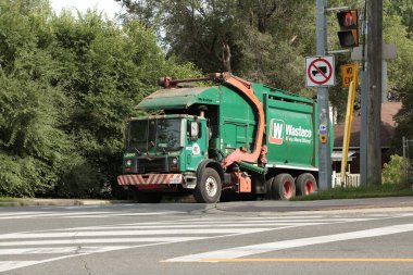 Wasteco park etmiş yeşil turuncu çöp kamyonu ile caddenin önündeki yol arasında büyük bir fark yaratıyor.