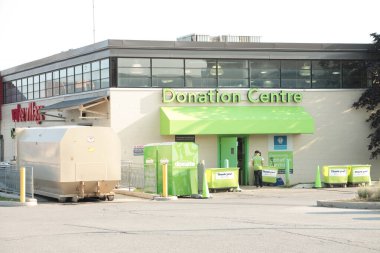 Değer Köyü Bağış Merkezi Logosu mağazanın arka tarafında. Arka girişte. Dışarıdaki işçiler binaya bakıyor.