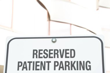 Rezervasyonlu hasta park yeri yazıları. Parlak ofis binası arkasında imza, beyaz arkaplanda siyah yazı, kapat.