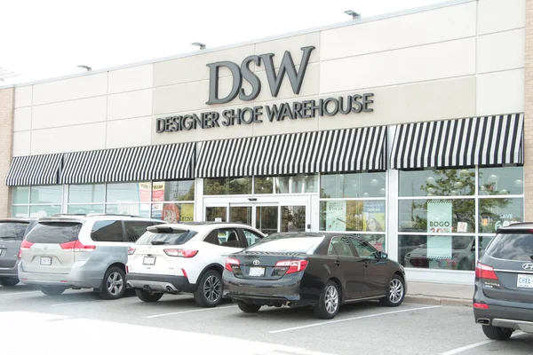DSW tasarımcı ayakkabı deposu ön girişi önünde arabaların park ettiği araç, dışarıdaki mağazanın önünde siyah ile işaret logosu yazıyor.
