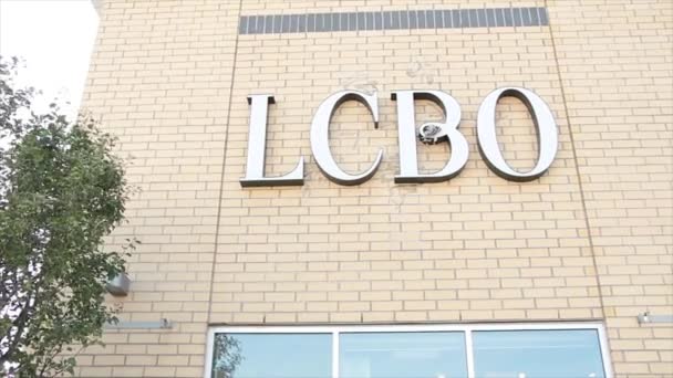 Lcbo アルコール コントロール ボードのオントリオのロゴの印の手紙は吹く木が付いている店の側面のテキストを書きます — ストック動画