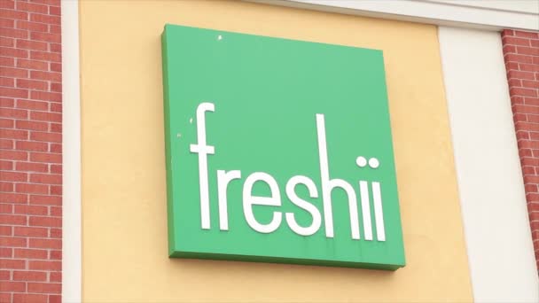 在绿色正方形的墙上用白字写着 Freshii Store 餐厅标志 — 图库视频影像