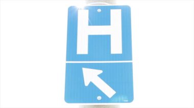 H harfi, ok mavisi dikey dikdörtgen işareti, büyük harf h ve ok işareti, kuzeybatıyı işaret ediyor, beyazlar içinde, açık havada, dışarıda, dışarıda, güneş arkamızda.