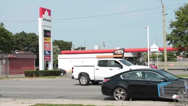 ペトロ カナダのガソリンスタンドは 車両の交通自転車が通過する道路を横切って撮影しました — ストック動画