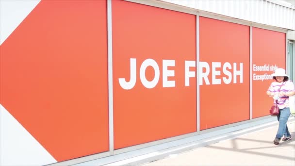 ジョー新鮮なブランドのロゴ広告オレンジ色の矢の白い執筆人歩行者が付いている外壁の窓の外側 — ストック動画