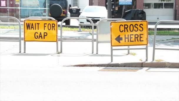 ここでギャップを待って 矢印を書くキャプションテキスト道路標識とクロス 黒の道路の真ん中で 車の交通が後ろを通過する黄色で — ストック動画
