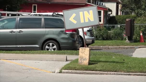 ワードキャプションのテキストは 後ろのカートを車輪で歩いている人と一緒に駐車場の入り口に左に矢印を付けて草の上の灰色の背景に黄色でサインを書きます — ストック動画