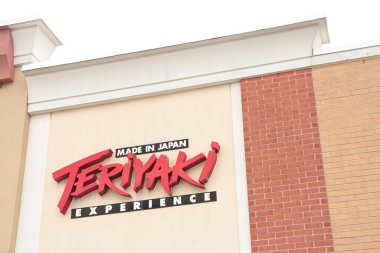 Teriyaki deneyimi, Japonya restoranındaki mağaza zinciri amblemi tabelasında bej üzerine kırmızı siyah beyaz bina duvarıyla yapılmış.