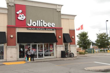 Jollibee Tavuk Burgerleri spagetti dükkanı girişi önünde insanların durduğu işaret amblemi olan.