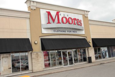 Moore 'un erkek kıyafetleri mağazanın ön girişinde, önünde kırmızı logo işareti olan açıyla çekilmiş.