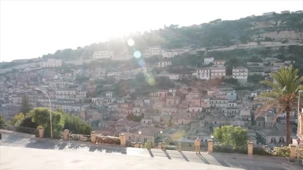 意大利莫迪卡市的一座山 房子建在圣乔吉奥大教堂的大房子里 阳光在山上闪耀 汽车在公路上经过 — 图库视频影像