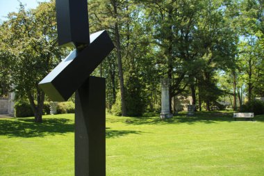 Lonca loncası, dikdörtgen şeklindeki siyah metal yapı. Arkası ağaçlarla çevrili. Orta ve alt kısımları yakın.