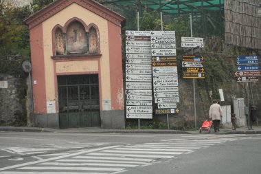 Amalfi Coast Village Caddesi yaya geçidi üzerinde bir sürü yön işareti ve caddeden karşıya geçen biri var.