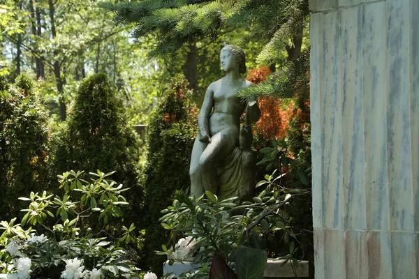 Lonca loncası heykeli ön planda sütunlu kadın figürü. Arka planda ağaçlar.