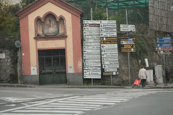 Amalfi Coast Village Caddesi yaya geçidi üzerinde bir sürü yön işareti ve caddeden karşıya geçen biri var.
