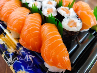 Nigiri suşisinin yakın plan görüntüsü, dilimlenmiş somonla kaplı tipik bir Japon yemeği.