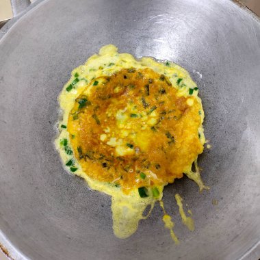 Taze soğan omleti tavada pişiriliyor, Asya usulü.