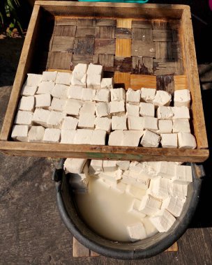 Bambu ahşap bir tahtanın üzerinde çiğ beyaz tofu ve kızartılmaya hazır beyaz tofu, tipik Endonezya sokak yemekleri.