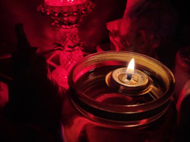 Oil lantern with flame burning in darkness on prayer altar table clipart