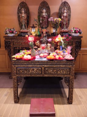 Jakarta, Indonesia - August 17, 2024 : A Buddhist altar filled with offerings of fruit, food and flowers at the Ekayana Vihara in West Jakarta, Indonesia. Buddhist religious events clipart