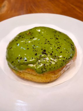 Krema soslu çörek ve beyaz tabakta çikolata tozu...