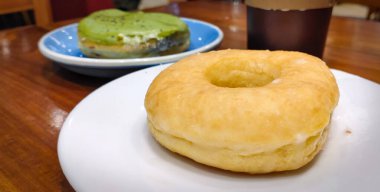 Özgün şekerli çörekler beyaz bir tabakta ve arka planda kibrit donutları var..