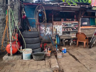 Jakarta, Endonezya - 24 Aralık 2024: Cakarta, Endonezya 'da sık sık yol kenarında bulunan küçük bir motosiklet tamirhanesi.