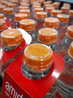 Cakarta, Endonezya - 14 Aralık 2024: Açık turuncu kapaklı temiz plastik su şişeleri süpermarket satış raflarında düzgünce düzenlenmiştir..