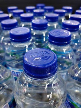 Cakarta, Endonezya - 14 Aralık 2024: Süpermarket satış raflarında düzgünce düzenlenmiş mavi kapaklı temiz plastik su şişeleri.