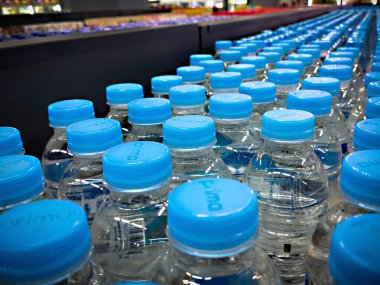Cakarta, Endonezya - 14 Aralık 2024: Açık mavi kapaklı temiz plastik su şişeleri süpermarket satış raflarında düzgün bir şekilde düzenlenmiştir..