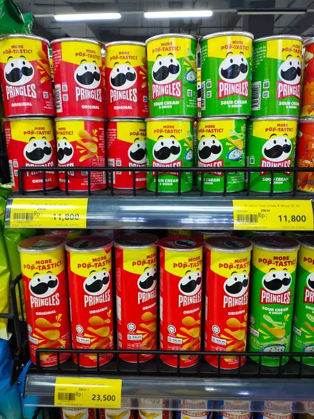 Jakarta, Endonezya - 21 Aralık 2024: Endonezya 'daki bir alışveriş merkezinde çeşitli aromalı Pringles marka patates cipsleri sergilenen süpermarket rafları.