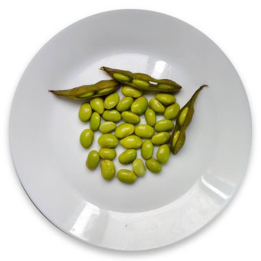 Edamame kapsülleri fasulyelerle haşlanarak pişirilir ve beyaz bir tabakta servis edilir..