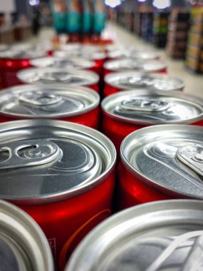 Düşük açılı çekim ve sığ alan derinliği bir süpermarkette düzgünce düzenlenmiş kırmızı soda kutularının tepelerine odaklanıyor..