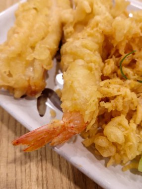 Masadaki beyaz tabakta servis edilen altın ve çıtır karides tempurası. Japon yemeği. Ulusal Tempura Günü 7 Ocak 'ta kutlanacak