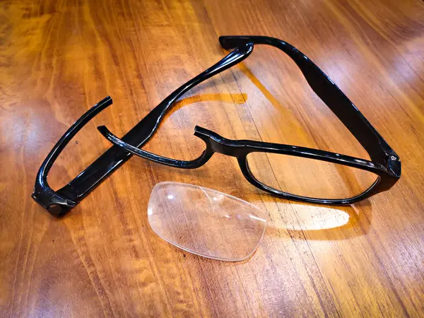 Kırık güneş gözlüğü ve mercekler ahşap bir yüzeyde duruyor.