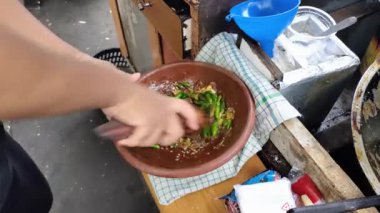 Bir tofu gejrot satıcısı kızarmış tofu gejrot için acı sos yapmak için yeşil biber, arpacık soğanı, sarımsak ve tuz karışımına vuruyor. Tofu gejrot, Endonezya 'nın Java adasında popüler bir sokak yiyeceğidir..